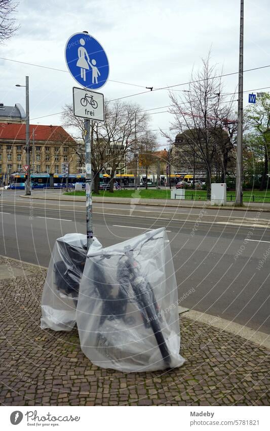 Transparent film as rain protection over an e-bike on the sidewalk with cobblestones in Goethestraße in Leipzig in the Free State of Saxony Wheel Bicycle