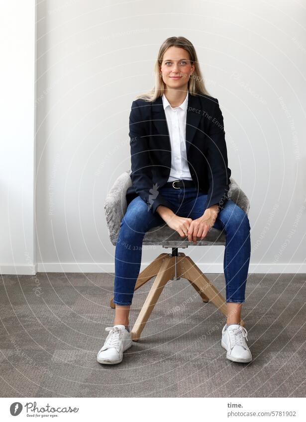 Woman in a seminar room Swivel chair sneakers Room Smiling Jacket Businesswomen Jewellery Armchair Long-haired Looking into the camera Blonde portrait Feminine