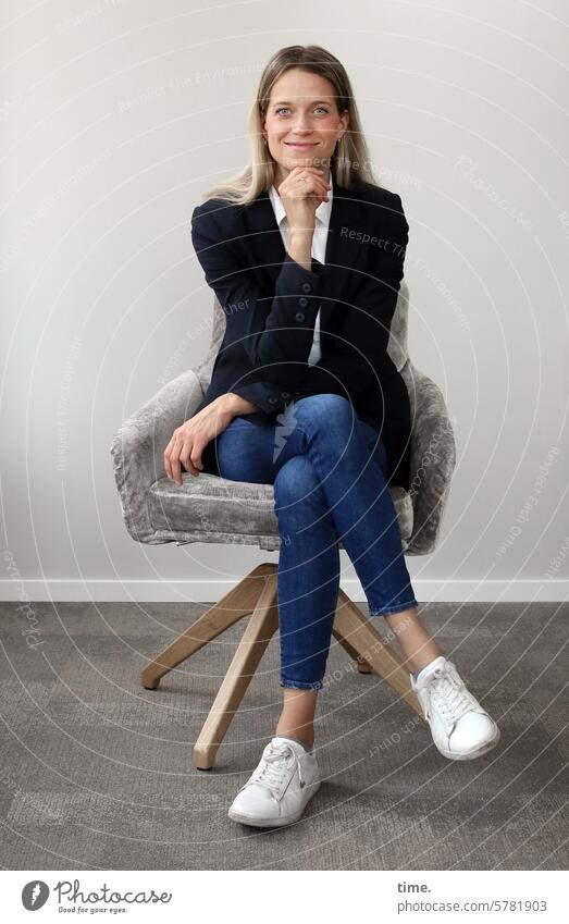 Woman in a seminar room Blonde portrait Feminine Hand Looking Looking into the camera Long-haired Jacket Businesswomen Jewellery Armchair Smiling Room sneakers