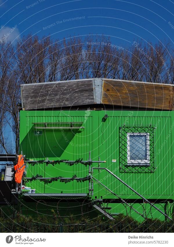 Verschlossener grüner Baucontainer mit Warnweste am Geländer vor blauem Himmel bauwesen Container sicherheit sicherheitsweste Grün Feierabend Außenaufnahme