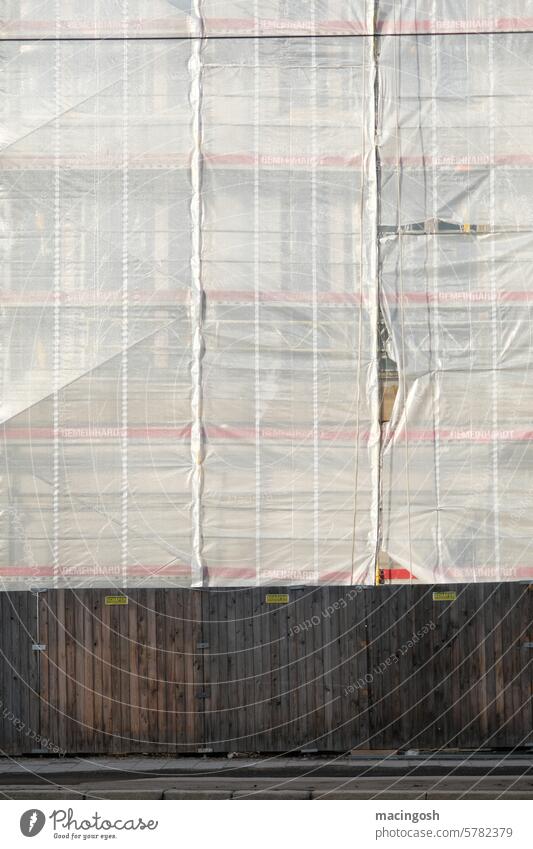 Frontal view of a construction fence with scaffolding Hoarding Scaffold construction industry Tarp unfinished Construction site Facade Covers (Construction)