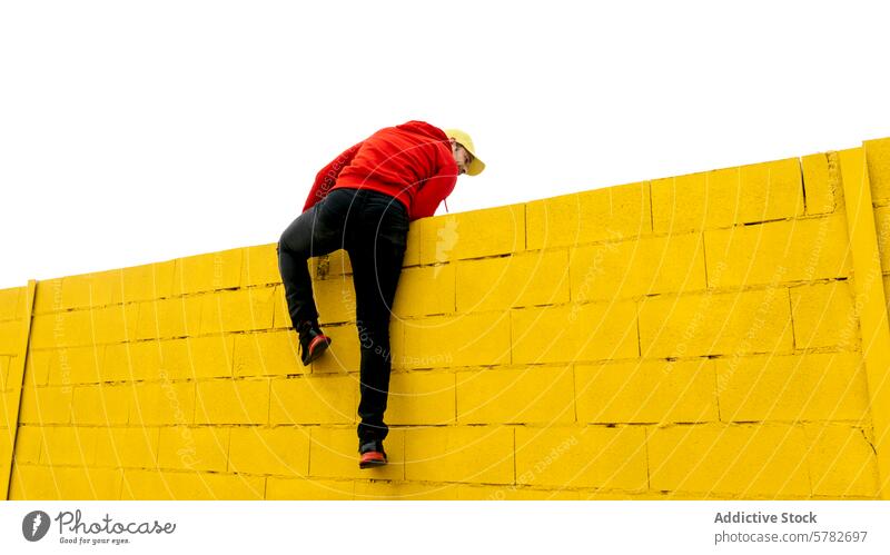 Climbing a bright yellow wall under a clear sky person red climb outdoor activity challenge effort overcoming obstacle adventure strength bold urban ascent