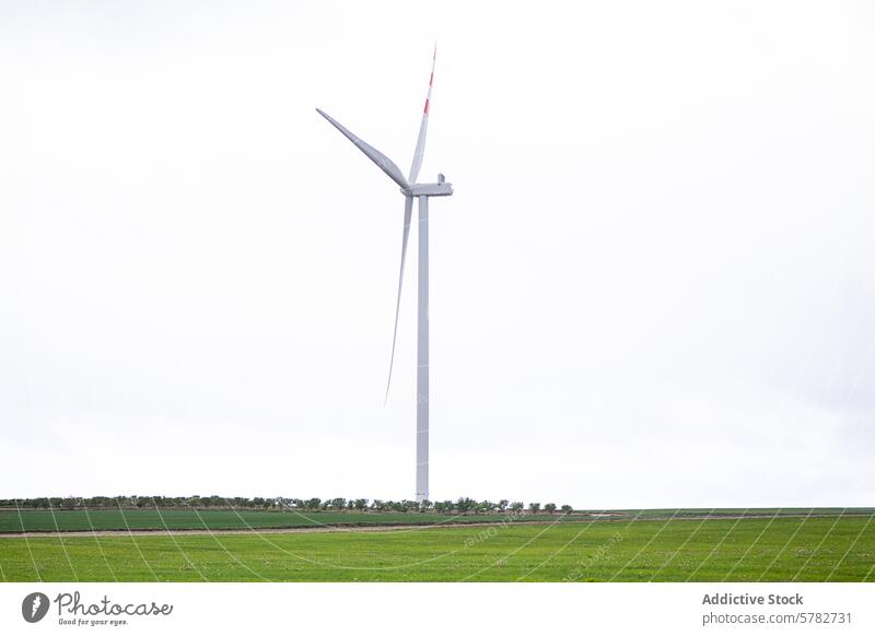 Lone wind turbine in a vast green field cloudy sky alternative energy single landscape environment sustainable technology power electricity generation