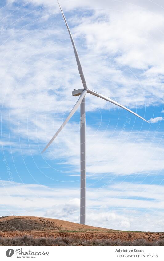 Sustainable wind energy in a rural landscape wind turbine sustainable energy cloudy sky blue hill barren eco-friendly renewable energy electricity generation