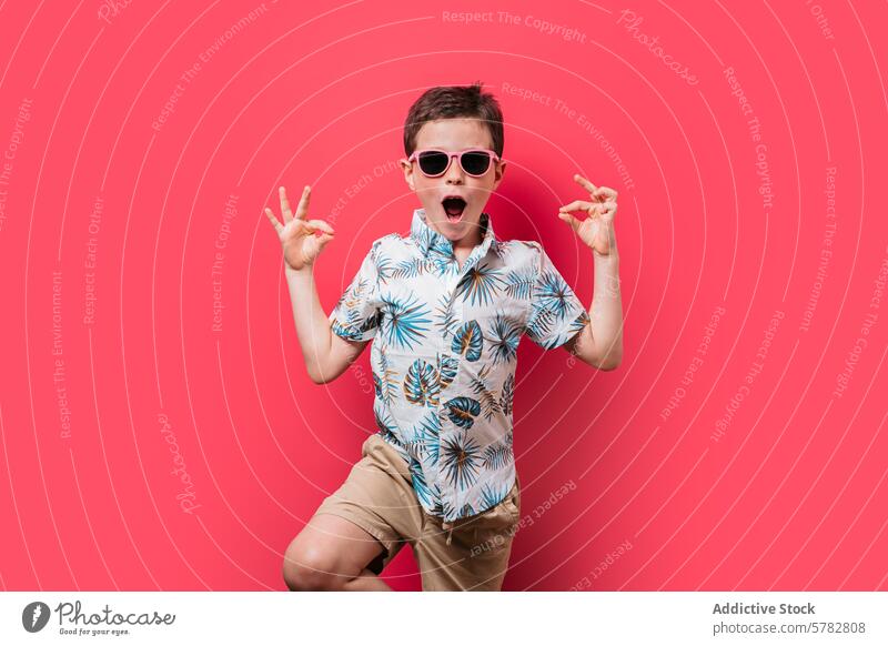Excited boy in tropical shirt and sunglasses posing child excited pink background gesture peace sign fun young fashion summer vibrant pose kid happiness joy