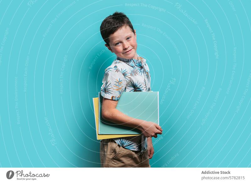 Smiling boy with folders on a turquoise background smile tropical shirt young cheerful education student relaxed vibrant casual holding portrait studio