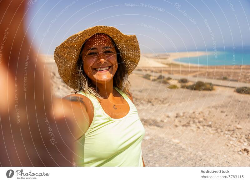 Smiling woman taking a selfie while hiking in Fuerteventura fuerteventura canary islands spain camping straw hat sunny cheerful rugged terrain adventure travel