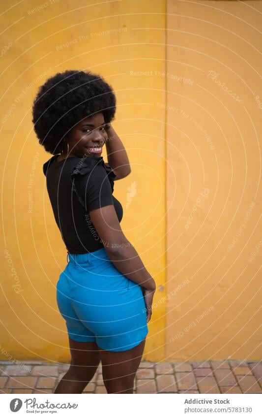 Portrait of a vibrant urban fashionable afro woman style portrait cheerful confident bright yellow wall chic trendy stylish pose young adult streetwear summer