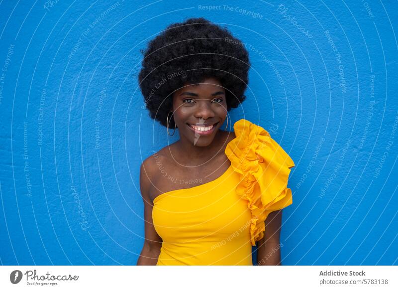 Smiling woman in yellow with blue backdrop afro smile yellow dress blue background vibrant joyful happy fashion lifestyle portrait hair african cheerful beauty