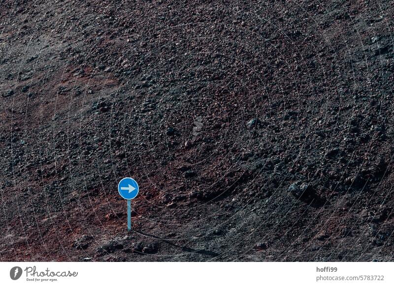 Small directional road sign in the wilderness in front of dark volcanic scree Trend-setting Road sign Wilderness Traffic infrastructure Volcanic Arrow Transport