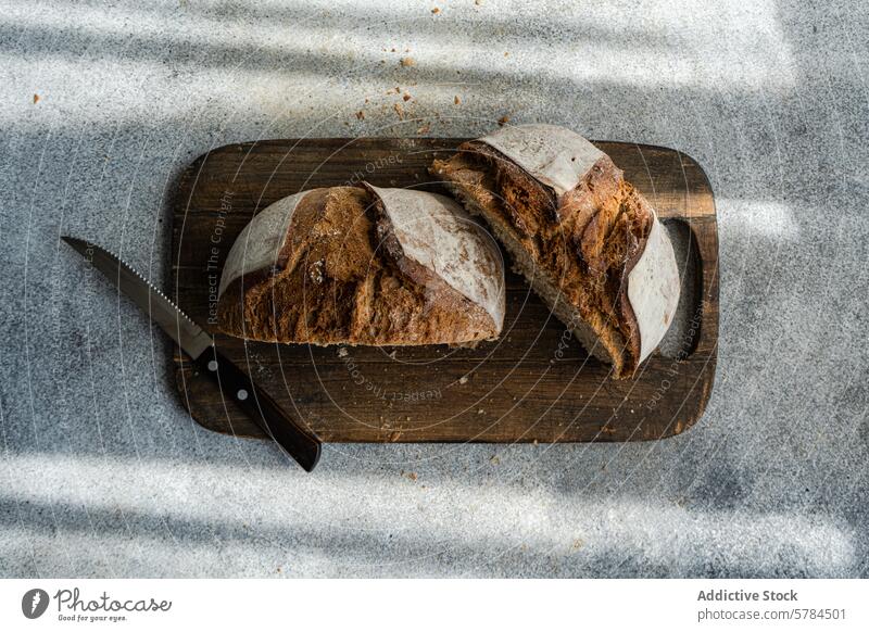 Artisanal Rye Sourdough Bread on Wooden Board bread rye sourdough artisanal healthy sliced wooden cutting board serrated knife shadow light rustic wholesome