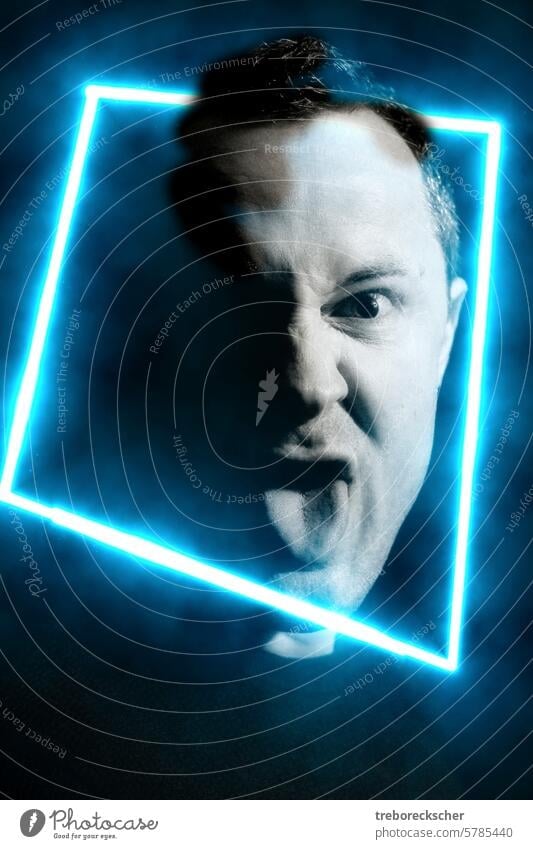 Stick out the tongue. Head Portrait of a man between 30 and 40 years in blue neon light square portrait head stick out male guy face lowkey black white angry