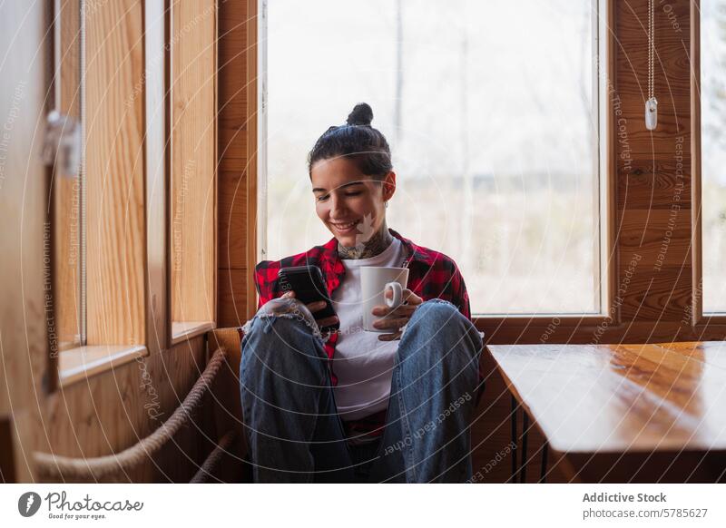 Cozy home setting with woman enjoying smartphone and coffee smiling window comfort relaxation sunlit room sitting enjoyment cozy indoor technology leisure