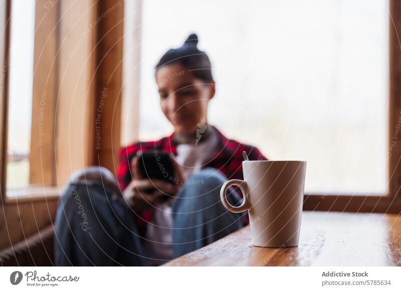 Cozy Coffee Break with Smartphone person coffee cup smartphone relaxing warm natural light sitting leisure break cozy window casual lifestyle comfort beverage