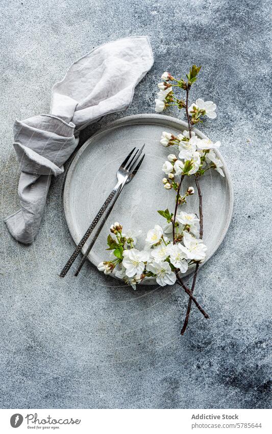 Elegant spring table setting with cherry blossoms wedding event theme plate linen napkin branch elegant sophisticated decor tabletop gray texture background