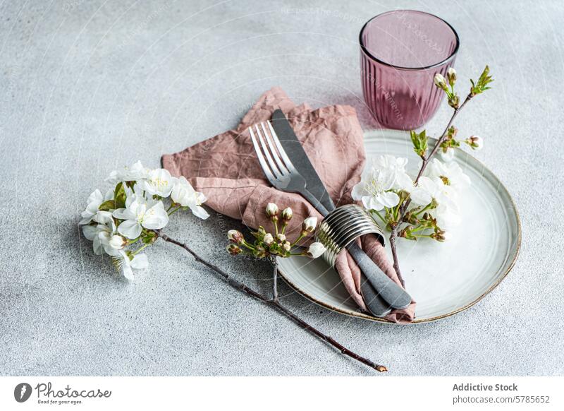 Elegant cherry blossom themed spring table setting spring theme elegant cutlery mauve napkin textured glass rustic plate arrangement branch sophisticated dining