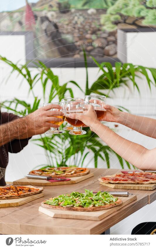Anonymous friends toasting with gluten-free beer over pizza celebration gourmet toppings good food cheers gathering social party drink ale handcrafted handmade