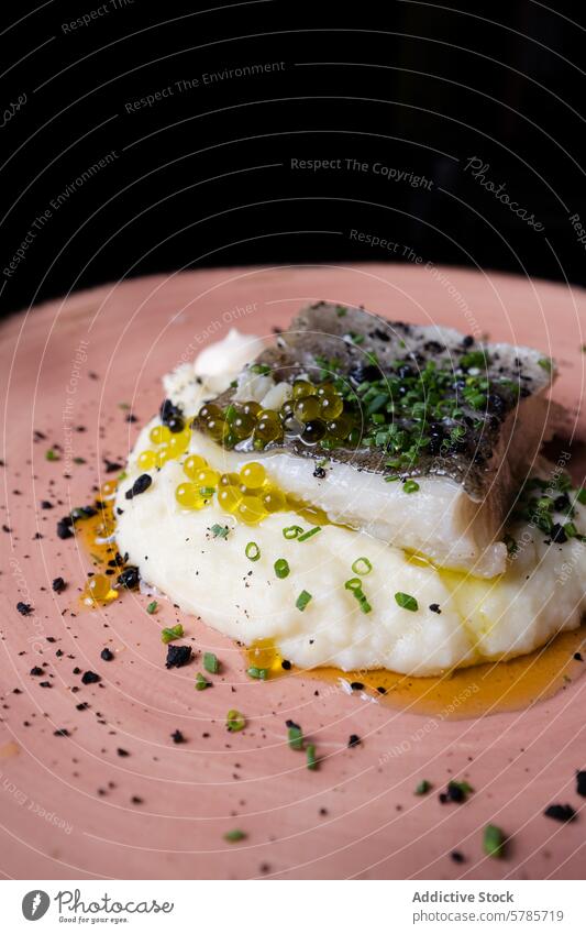 Cod confit on creamy mashed potato with chives cod olive oil pearl black sesame rustic plate pink gourmet bed garnish fresh vibrant succulent presented food