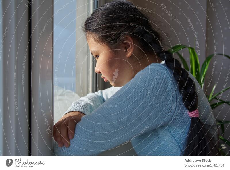 Contemplative girl gazing out of a window thought contemplation braid indoors reflection expression subtle daylight pensive looking young thoughtfulness