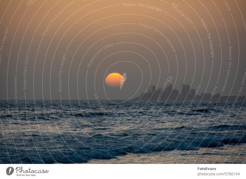 Sunset over the sea with a city in silhouette view Maspalomas copy space postcard Gran Canaria nature water dusk outdoor wall art background orange light