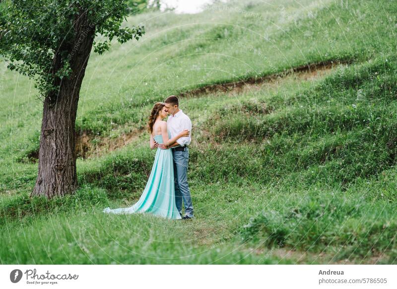 happy guy in a white shirt and a girl in a turquoise dress are walking in the forest park young grass trees bushes green brown day summer spring love nature