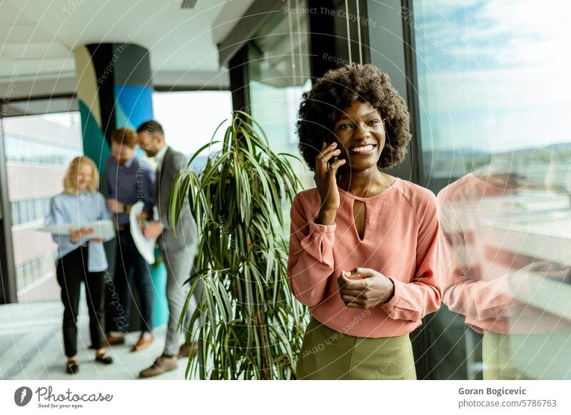Radiant African American businesswoman engaging in a bright conversation at office space during work hours phone call colleagues professional smiling workplace