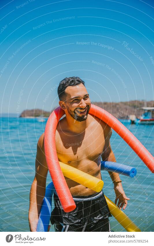Smiling man playing with colorful pool noodles at the beach smile water tropical leisure joy balance vibrant sunlit costa rica coast essence summertime fun