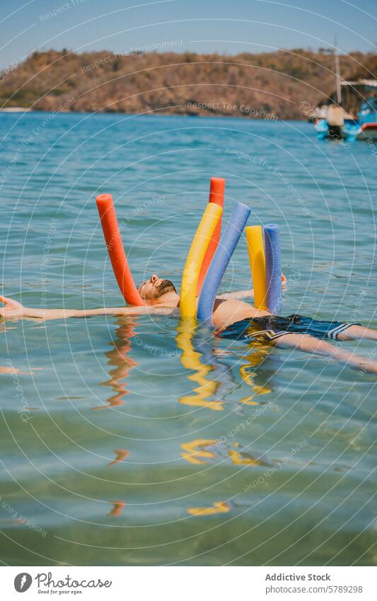Relaxing float with colorful pool noodles in Costa Rica waters costa rica relaxation swimming blue sea calm leisure vacation tropical coast person summer