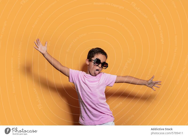 Energetic boy posing with sunglasses against a yellow background child studio pose oversized playful energy fun joyful young bright color fashion style