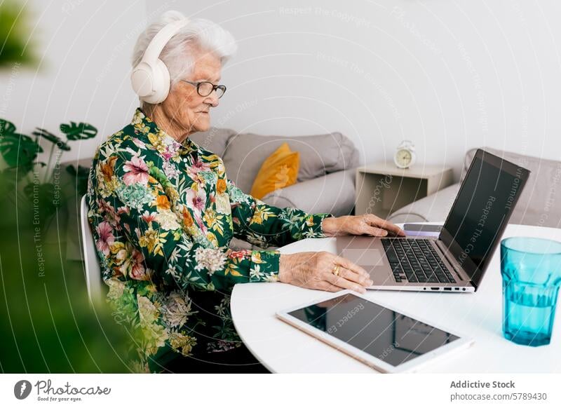 Senior woman embraces technology working from home senior laptop headphones elderly modern computer internet comfortable remote work freelance online wireless