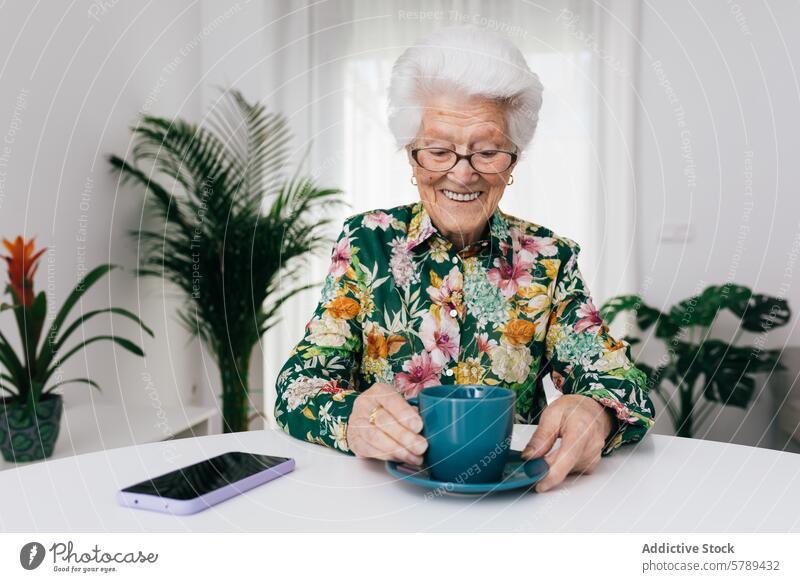 Elderly woman enjoying a cup of tea at home senior elderly floral blouse happiness white hair smiling glasses houseplant room domestic life leisure relax