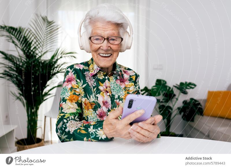 Senior Woman Enjoying Music at Home with Smartphone senior woman elderly headphones smartphone music home cheerful white hair happy technology modern leisure
