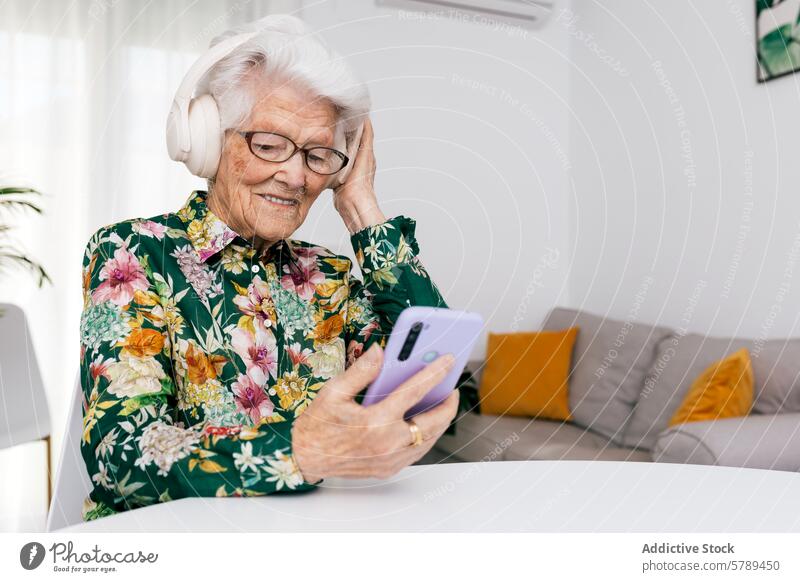 Elderly woman enjoys music and technology at home senior elderly headphones smartphone joyful white hair glasses indoor seated comfortable leisure lifestyle