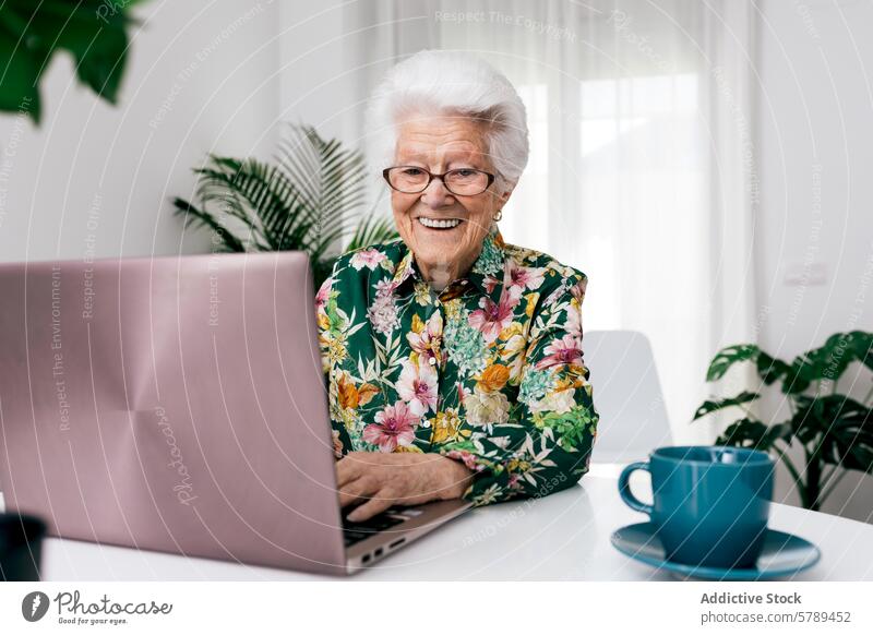 Senior woman using laptop at home with a joyful expression senior working cheerful elderly coffee confidence happiness technology internet user computing online
