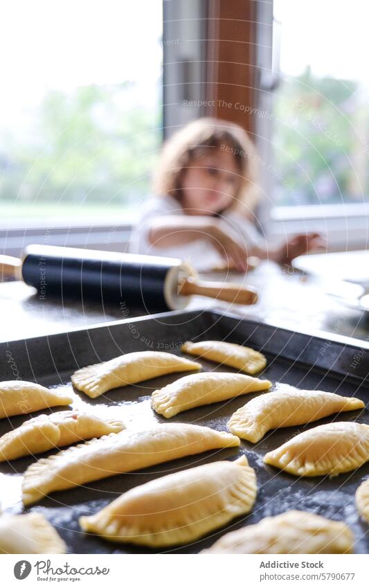 Child baking homemade pastries in cozy kitchen child pastry family cooking dough rolling pin tray domestic life blurred background food preparation baking sheet