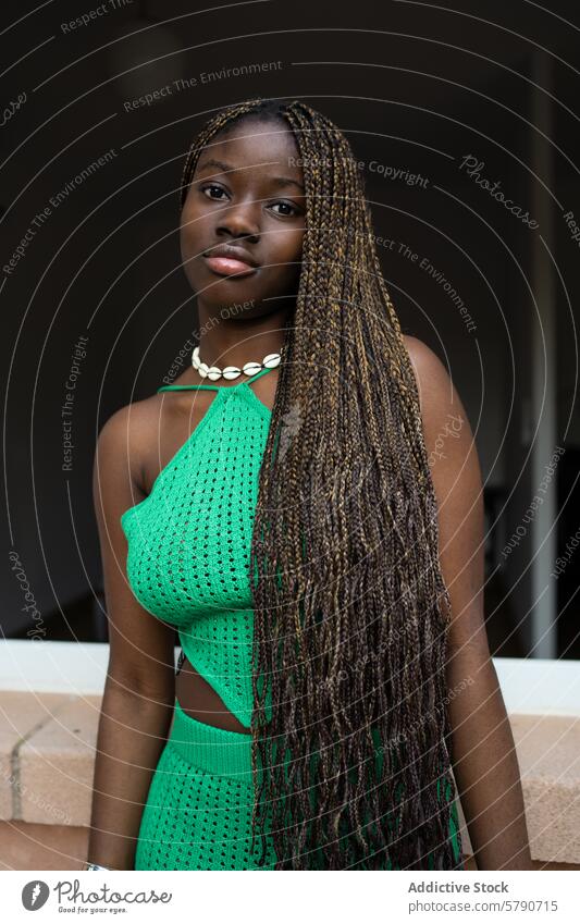 A poised young black woman with intricate braids wears a vibrant green crochet dress, exuding confidence and style fashion elegance youth chic modern casual