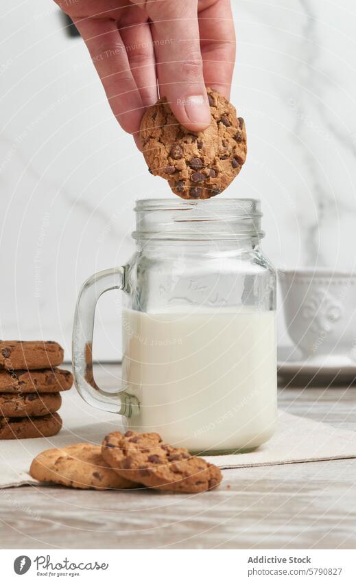 Dunking a chocolate chip cookie in milk dunk hand jar fresh snack sweet treat dessert homemade table wood glass beverage dairy indulgent food stack fabric
