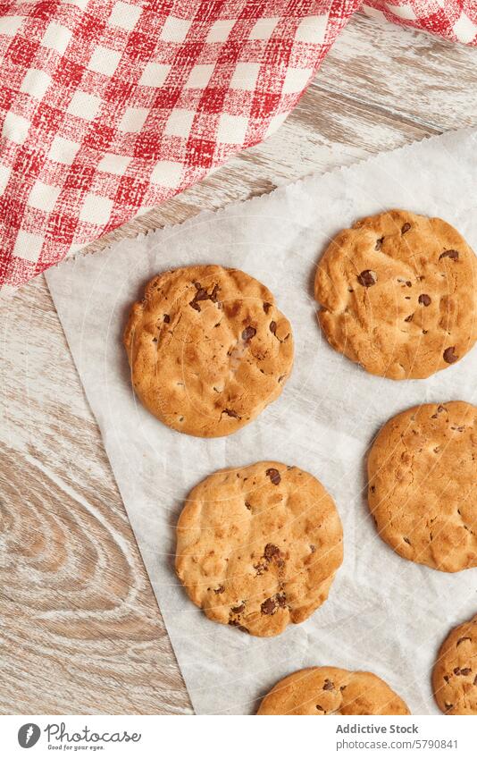 Delicious chocolate chip cookies on a rustic table parchment paper gingham cloth wood snack dessert baked goods treat sweet homemade top view food tasty