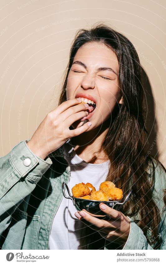 Woman enjoying delicious fried mozzarella bites woman eating cheese snack happy enjoyment casual food indulgence taste young adult smiling holding golden crispy