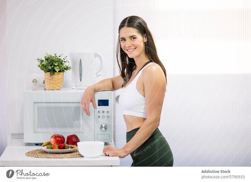 Fitness woman with healthy food in kitchen fitness modern home athletic wear smile preparing meal fresh fruit sportswear wellness lifestyle nutrition eating