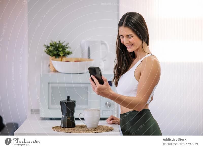 Athletic woman enjoying a break at home athletic smartphone kitchen smile modern activewear fit health wellness technology leisure casual comfortable domestic