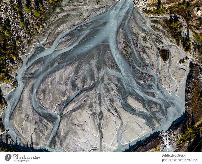 Overhead image captures the intricate patterns of a braided river system surrounded by rugged terrain, highlighting nature's artwork aerial landscape waterway