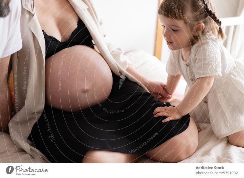 Little girl next to her pregnant mother pregnancy child belly touching family love expecting young tender moment emotion bond motherhood maternity care