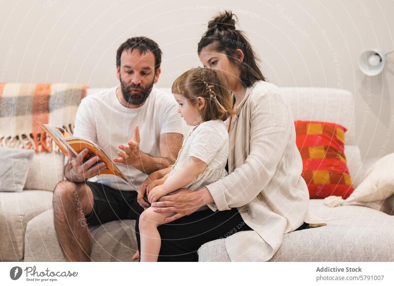 Family storytime on a cozy sofa family reading book child parents education learning bonding storytelling mother father daughter home leisure indoor comfort