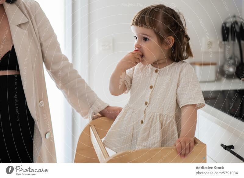 Thoughtful toddler girl with adult in a modern kitchen child woman contemplation indoor thoughtful expression lifestyle family everyday moment casual home