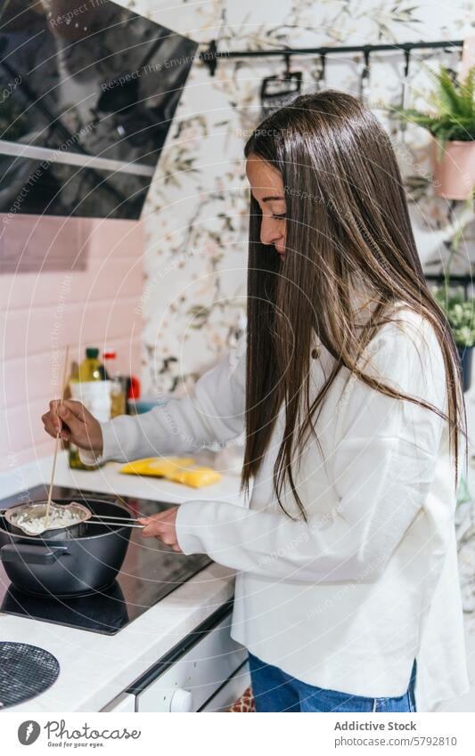 Woman Cooking in a Stylish Kitchen Interior woman cooking stove kitchen stylish floral wallpaper interior home cookware pot stirring food preparation