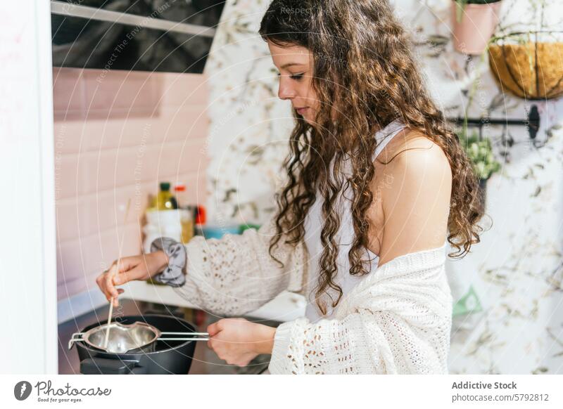 Young woman attentively cooking in a home kitchen curly hair stirring pot stove focus cozy curly-haired young interior domestic lifestyle food preparation