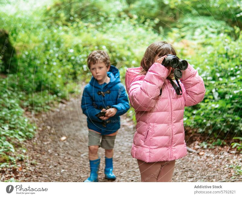 Grandchildren exploring nature with binoculars and compass grandchild grandson exploration walk outdoor leisure family experience boy girl jacket pink blue