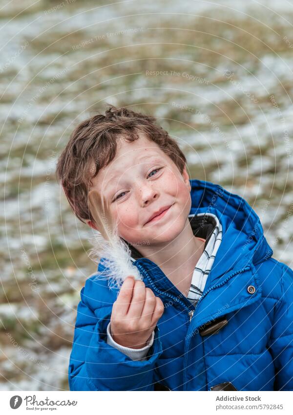 Smiling boy outdoors holding a feather smile childhood happiness leisure play fun family day jacket blue winter cold curly hair cheerful playful moment nature