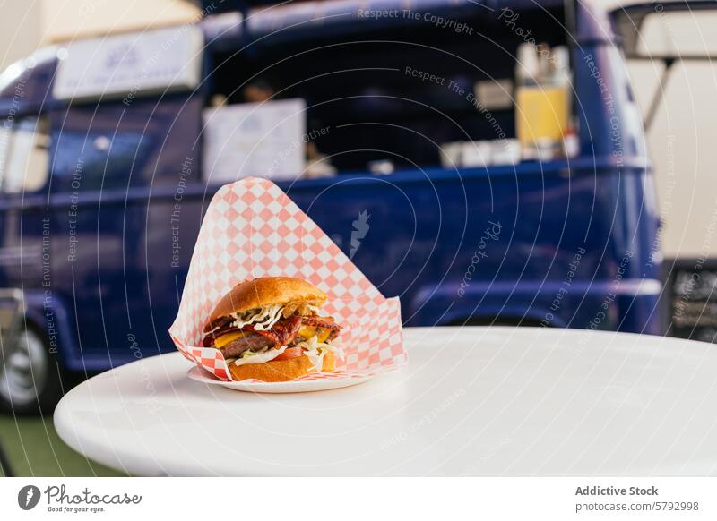 Gourmet burger served at a vibrant food truck setup gourmet street food tabletop blue checkered paper serving delicious fast food outdoor catering event bacon